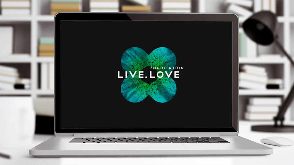 Ноутбук на столі з логотипом LIVE.LOVE Meditation на екрані, що демонструє сайт або додаток