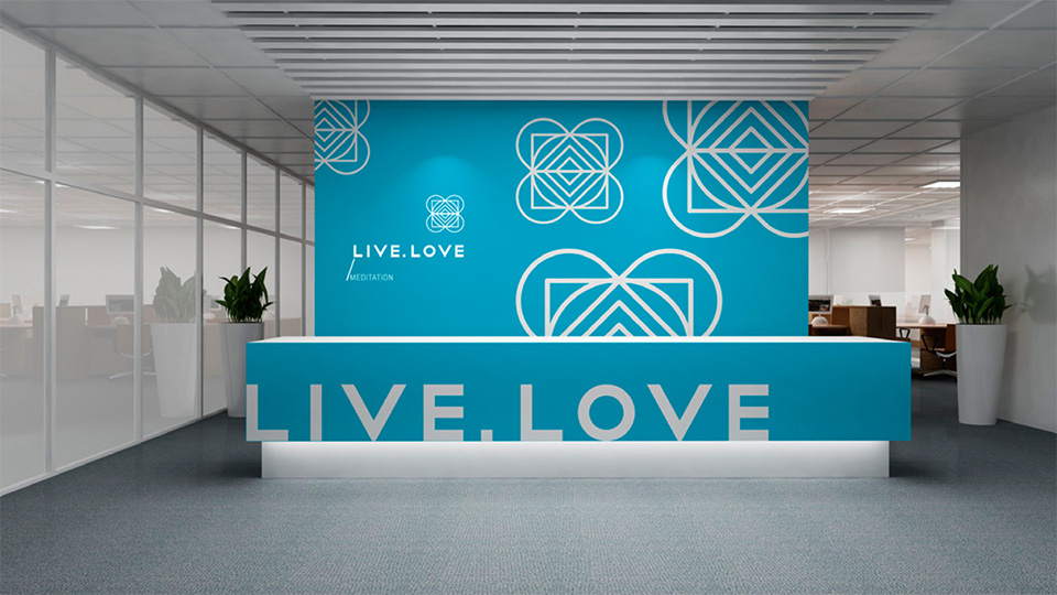 Брендована стійка рецепції та стіна в офісі LIVE.LOVE Meditation з бірюзовим логотипом та патерном