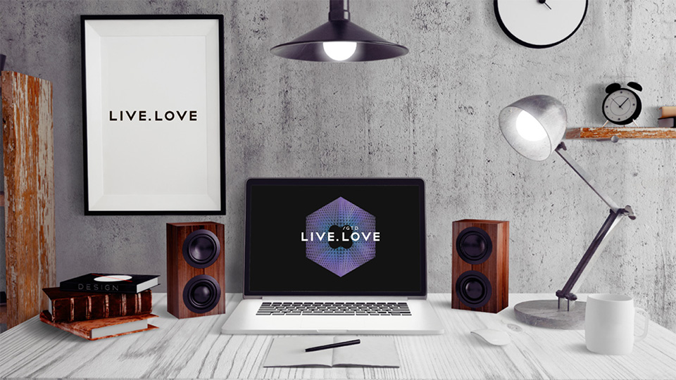 Сучасне робоче місце з ноутбуком, на екрані якого логотип LIVE.LOVE GTD, та постером LIVE.LOVE на стіні