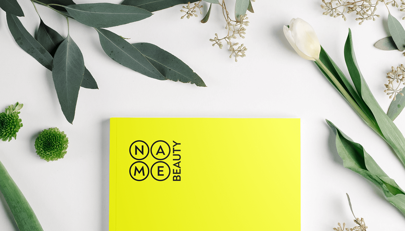 Мокап логотипу Name Beauty на жовтій картці серед зеленого листя та квітів - бренд-ідентичність для косметичного бізнесу Київ