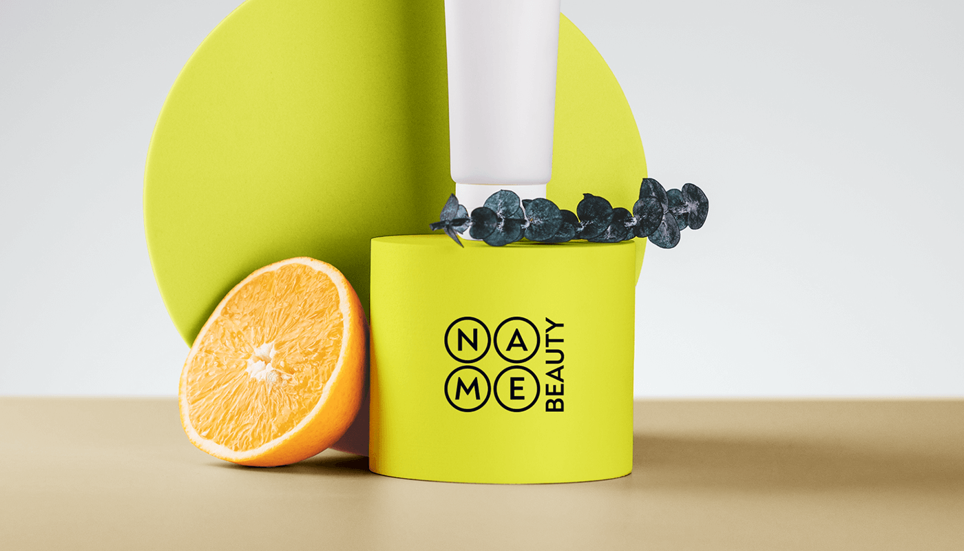 Мокап логотипу Name Beauty на жовтій упаковці поруч з тюбиком косметики та апельсином - візуальний стиль для дистриб'ютора косметики Київ