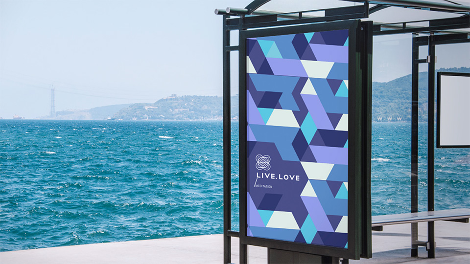 Зовнішня реклама LIVE.LOVE Meditation на зупинці громадського транспорту біля моря: постер з логотипом та синім патерном